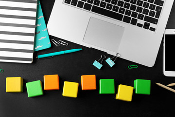 Wall Mural - Laptop, copybook and wooden cubes on color background