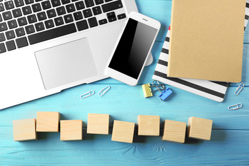 Poster - Laptop, copybook and wooden cubes on color background