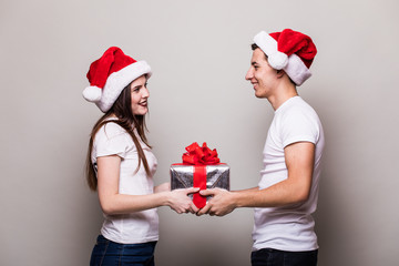 Happy couple share christmas gift on grey background