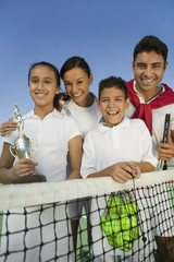 Wall Mural - Tennis Family at net on tennis court daughter holding trophy portrait