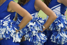 Midsection Of Young Female Cheerleaders Holding Pom-poms