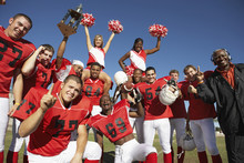Portrait Of Happy Football Team With Cheerleaders And Coach Celebrating Success On Field