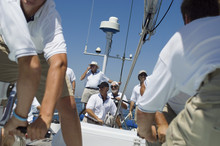 Portrait Of A Smiling Sailor With Crew On The Sailboat Deck Against Clear Sky