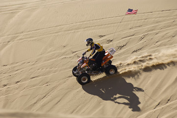 Wall Mural - High angle view of a quad racer riding over sand dune