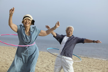 Couple with hula hoops on beach