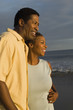 © moodboard - Happy young African American couple looking away on beach