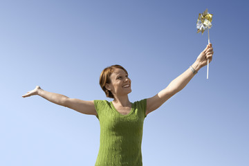 Happy cheerful woman holding a pinwheel against clear sky