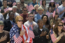 Group Of Multiethnic People Singing American National Anthem And Holding American Flags