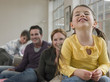© moodboard - Cheerful little girl with family sitting on sofa at home