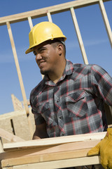 worker carrying wooden beams at construction site