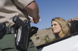 © moodboard - Young woman looking at mature traffic officer checking her license