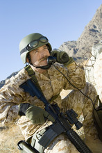 Mature Army Soldier With Rifle Using Telephone