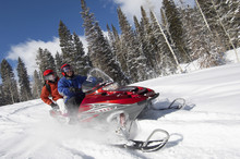 Couple Driving Snowmobile On Snow Covered Track