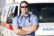 © moodboard - Portrait of a confident male paramedic worker standing in front of an ambulance