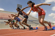© moodboard - Group of diverse female athletes taking off from starting blocks in race