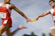 Blurred Motion Male Runners Passing Baton In Relay Race