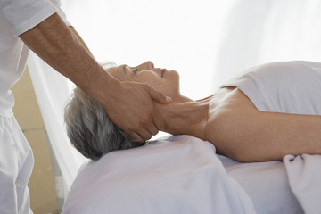 Side view of a senior woman receiving massage at spa