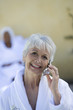 © moodboard - Portrait of a smiling senior woman in bathrobe using mobile phone