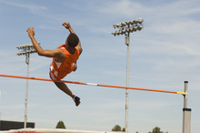 Male Athlete Performing High Jump Against Sky