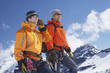 © MDBPIXS - Two male mountain climbers on snowy peak against sky with one using walkie talkie
