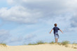 © MDBPIXS - Rear view of a young boy standing on sand dune in wind with arms outstretched