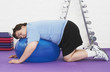 © moodboard - Side view of an overweight man sleeping on exercise ball in health club
