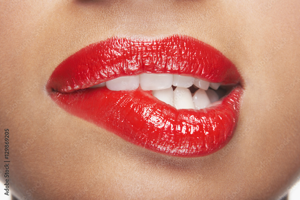 Closeup of sensuous woman biting red lips - obrazy, fototapety, plakaty 