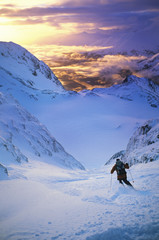 Rear view of skier moving down slope at sunset