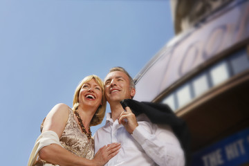 Low angle view of a well dressed smiling couple standing against building and sky