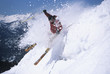 Side view of a male skier skiing through powdery snow on ski slope