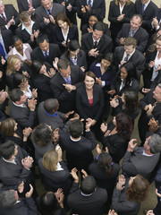 Elevated view of business group looking at female woman standing in middle