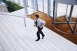 © MDBPIXS - Elevated view of young businessman running upstairs in office lobby