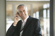 © MDBPIXS - Happy middle aged businessman using mobile phone in office