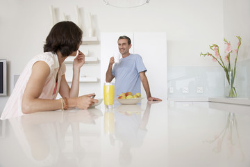 Middle aged couple having breakfast at kitchen bench