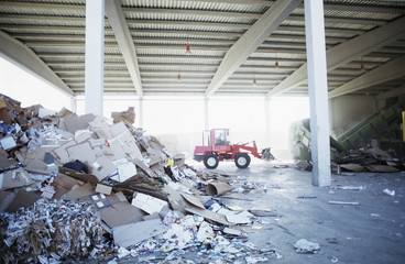 Wall Mural - Heap of paper waste with digger truck in background at recycling plant