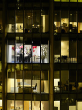 View Of Business People Having Office Party Through Window At Night