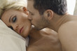Closeup of a young man kissing woman's cheek in bed