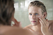 © MDBPIXS - Closeup of handsome young man applying facial cream in front of mirror
