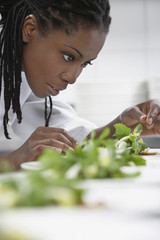 Wall Mural - Closeup side view of a female chef preparing salad in kitchen