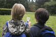 Rear view of two young boys with backpacks using compass