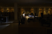 Side View Of A Young Woman Working On Computer In Dark Office
