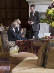 Wall Mural - Three businesspeople talking in lobby with sofas in foreground