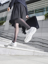 Lowsection Of A Businesswoman Wearing Running Shoes Walking Up Steps