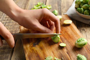 Wall Mural - Female hands cutting Brussels sprouts on wooden board