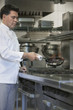 © MDBPIXS - Side view of a male chef cooking food using frying pan in kitchen