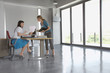 Full length side view of two female executives discussing document at desk in empty office