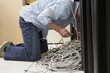 Side view of a man working on tangled computer wires in office