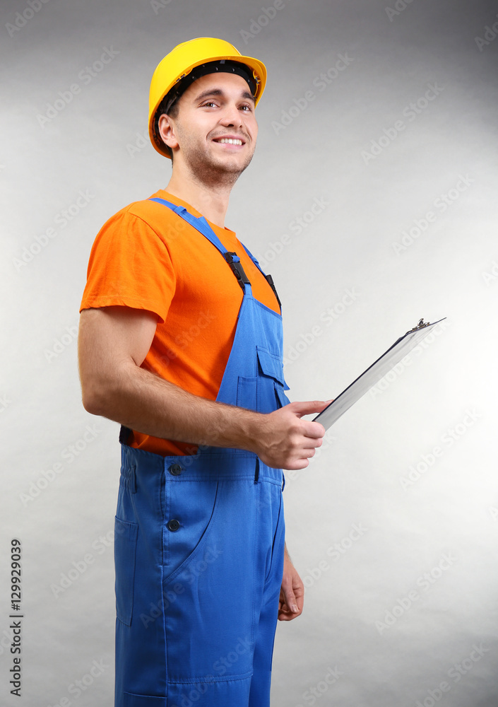 Handsome warehouse worker with clipboard on light background