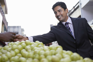 Wall Mural - Happy young businessman buying grapes from fruit vendor