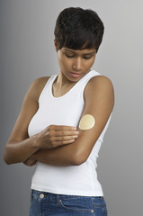 an african american woman with nicotine patch on arm over grey background